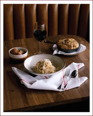 a table with a plate of pasta and a glass of wine at Sechelt inn in Sechelt
