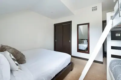a white bedroom with a bed and a staircase at Heavenly Mountain Condo managed by Little Sister Getaways in Canmore