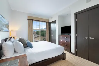 a bedroom with a large bed and a television at Heavenly Mountain Condo managed by Little Sister Getaways in Canmore