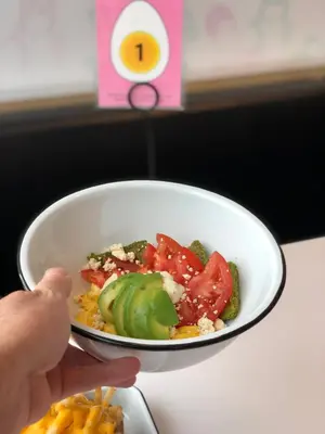a person holding a plate of food with a bowl of vegetables at Alt Hotel Calgary East Village in Calgary