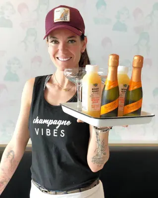 a woman holding a tray of bottles of beer at Alt Hotel Calgary East Village in Calgary