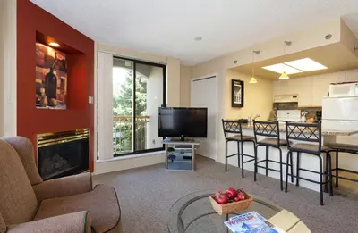 a living room with a television and a kitchen at The Marquise by Whistler Premier in Whistler