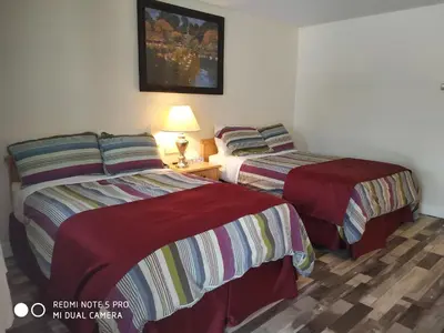 a bedroom with two beds and a table with a lamp at Pleasant Valley Motel Houston in Houston