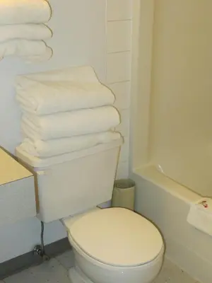 a bathroom with a toilet and a stack of towels at Lazy J Motel in Claresholm