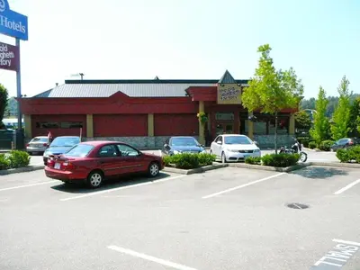 a red car parked in a parking lot in front of a store at Coast Abbotsford Hotel & Suites in Abbotsford
