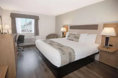 a bedroom with a bed and a desk and a window at Coast Abbotsford Hotel & Suites in Abbotsford