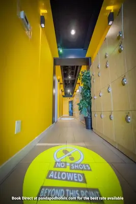 a yellow room with a no shoes allowed sign on the floor at Panda Pod Hotel in Richmond