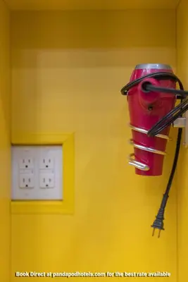 a red bucket hanging on a wall next to a lightswitch at Panda Pod Hotel in Richmond