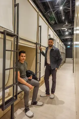 two men are standing in a hallway in a room at Panda Pod Hotel in Richmond