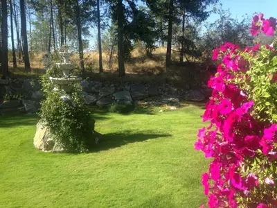 a garden with a stone wall and pink flowers at Eagle's Nest B&B in Lake Country
