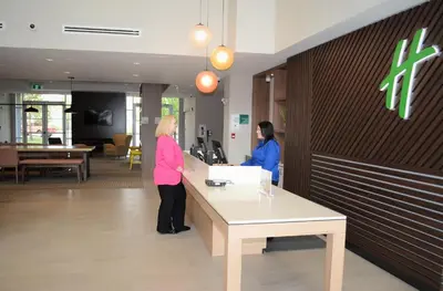 two people standing at a counter in a lobby at Holiday Inn Edmonton South - Evario Events by IHG in Edmonton
