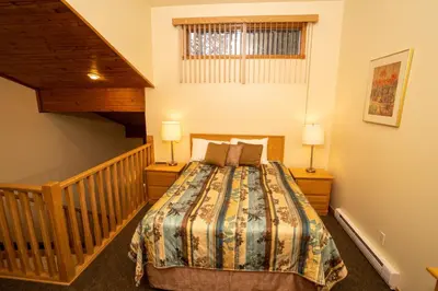 a bedroom with a bed and a staircase with two lamps at Fairmont Hot Springs Resort in Fairmont Hot Springs