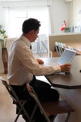 a man sitting at a table with a laptop computer at Painted Turtle Guesthouse in Nanaimo
