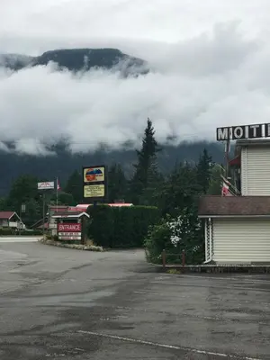 a parking lot in front of a mountain with clouds at Inntowne Motel in Hope