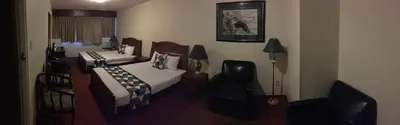 a bedroom with two beds and a chair and a window at Spring Villa Hotel in Harrison Hot Springs