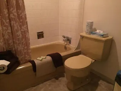 a bathroom with a toilet and a bathtub with towels at Spring Villa Hotel in Harrison Hot Springs