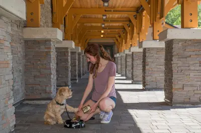 a woman kneeling next to a dog with a camera at Executive Suites Hotel and Resort, Squamish in Squamish