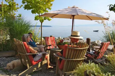 a group of people sitting in chairs under an umbrella at Blitz Beach House Oceanside Suite in Powell River