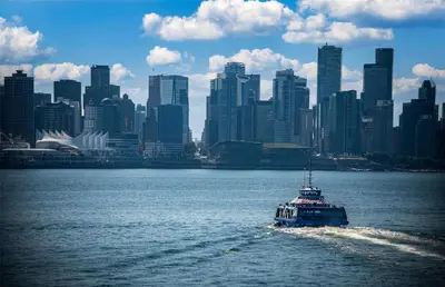 a boat in the water in front of a city at Coast Lonsdale Quay Hotel in North Vancouver