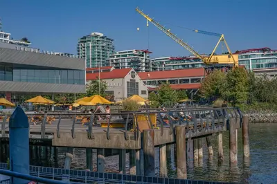 a pier with tables and yellow umbrellas in a city at Coast Lonsdale Quay Hotel in North Vancouver