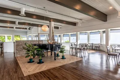a dining room with tables and chairs and windows at Bayside Resort, an Ascend Collection Resort in Parksville