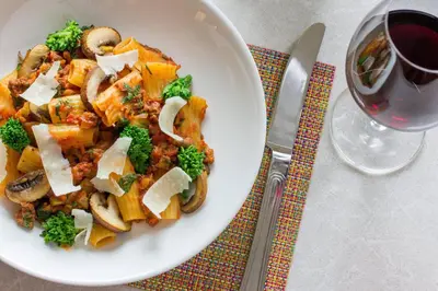 a white bowl of food with mushrooms and a glass of wine at JW Marriott Edmonton ICE District in Edmonton