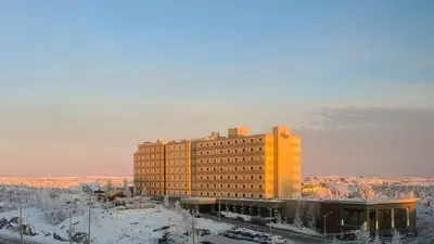 a large yellow building with snow on the ground at The Explorer Hotel in Yellowknife
