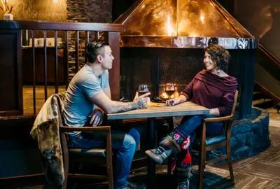 a man and woman sitting at a table with wine glasses at The Explorer Hotel in Yellowknife
