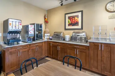 a coffee shop with wooden cabinets and a table and chairs at Devonian Hotel and Suites in Fox Creek