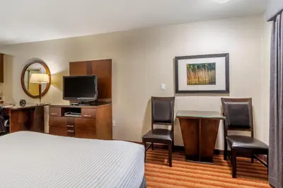 a hotel room with a bed and a table and chairs at Devonian Hotel and Suites in Fox Creek