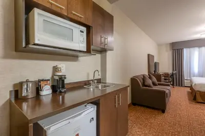 a kitchen with a sink and a microwave in a hotel room at Devonian Hotel and Suites in Fox Creek