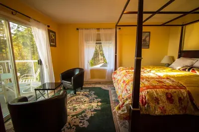 a bedroom with a bed and a chair and a window at Rae Leigh Heights BnB in Saanichton