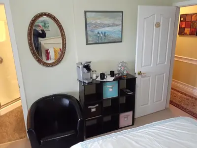 a bedroom with a black chair and a mirror at Rae Leigh Heights BnB in Saanichton