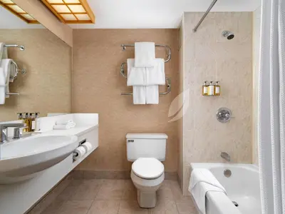 a bathroom with a toilet and a sink and a tub at Inn at Laurel Point in Victoria