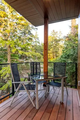 a table and two chairs on a deck with a view at Storm Cove Suites in Ucluelet