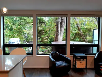 a room with large windows and a black chair at Storm Cove Suites in Ucluelet