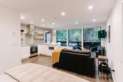 a living room with a couch and a kitchen at Storm Cove Suites in Ucluelet