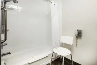 a bathroom with a white chair next to a shower at Holiday Inn & Suites Grande Prairie by IHG in Grande Prairie