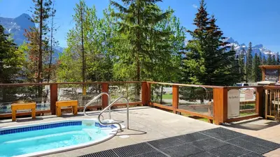 a hot tub on a deck with a view of the mountains at ⭐️ Luxury Mountain View Studio in Canmore ⭐️ in Canmore