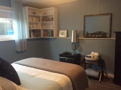 a bedroom with a bed and a mirror and a window at Berkie’s Bed & Breakfast in Port Alberni