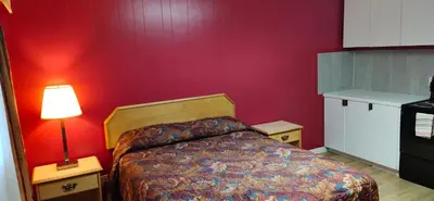 a bedroom with a bed and a red wall at Gold Pan Motel in Quesnel