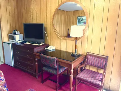 a room with a desk with a mirror and a television at Gold Pan Motel in Quesnel