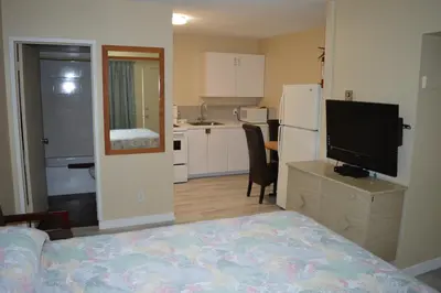 a room with a bed and a kitchen with a television at Gold Pan Motel in Quesnel