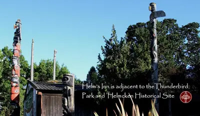 a sign for a park and habitatlisted site with totem poles at Helm's Inn in Victoria