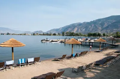 a group of chairs and umbrellas on a beach at Walnut Beach Resort in Osoyoos