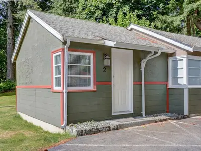 a small green house with a white door and a window at Malahat Bungalows Motel in Malahat