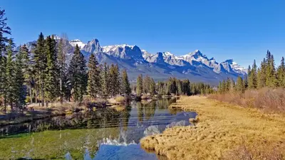 a river with snow capped mountains in the background at Downtown Loft, Mountain Views, Fireplace, Couple's Retreat, Walker's Paradise in Canmore