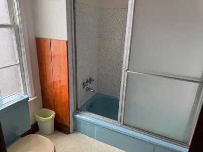a bathroom with a shower with a blue tub at Rodmay Hotel in Powell River