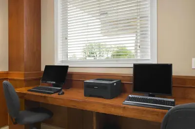 two computers sitting on a wooden desk with a window at Days Inn by Wyndham Chetwynd in Chetwynd