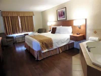 a hotel room with a bed and a bath tub at Rosslyn Inn & Suites in Edmonton